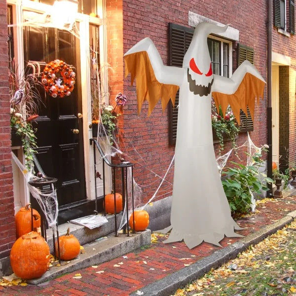 Halloween decorations including a ghost inflatable, pumpkins, and spider webs on a brick building.